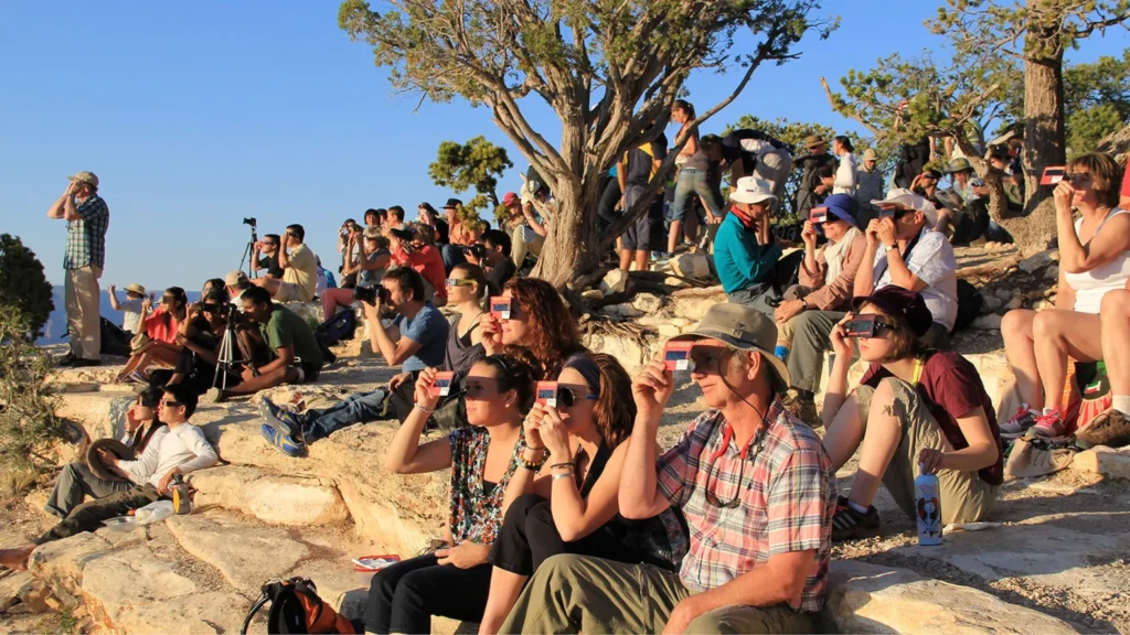 A crowd uses handheld solar viewers and solar eclipse glasses to safely view a solar eclipse